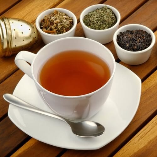 A cup of warm herbal tea on a saucer with spoon